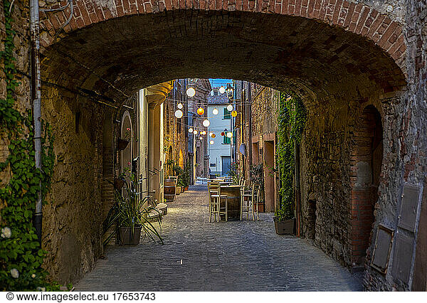 Italy  Province of Siena  Radicondoli  Lanterns illuminating old town alley with brick arch in foreground