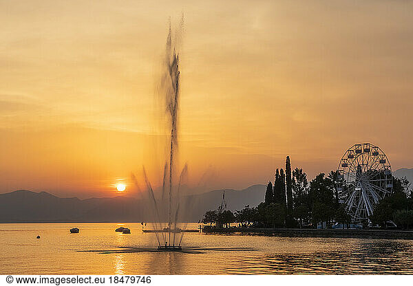 Italy  Veneto  Bardolino  Lake Garda fountain splashing against setting sun