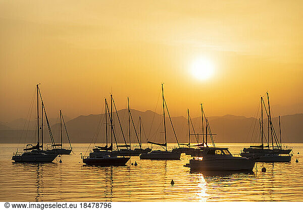 Italy  Veneto  Bardolino  Silhouettes of sailboats floating in Lake Garda at sunset
