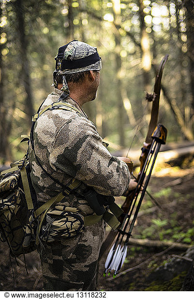 Jäger mit Pfeil und Bogen im Wald stehend