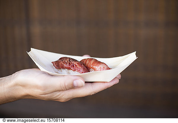 Japan  Hand of woman holding tray of Japanese hida beef