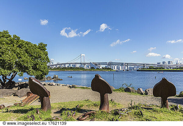 Japan  Kanto Region  Tokyo  Rusty anchors on shore of Tokyo Bay with Rainbow bridge in background