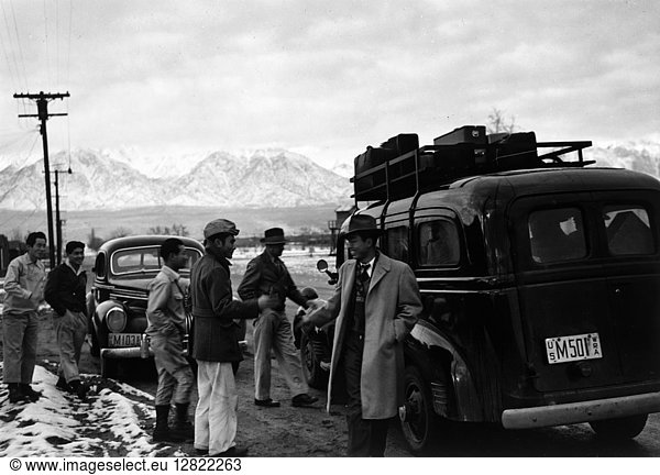 JAPANESE INTERNMENT  1943. Group of men gathered around a car packed with passengers and luggage  about to depart from the Manzanar Relocation Center for Japanese-Americans at Owens Valley  California. Photograph by Ansel Adams  1943.