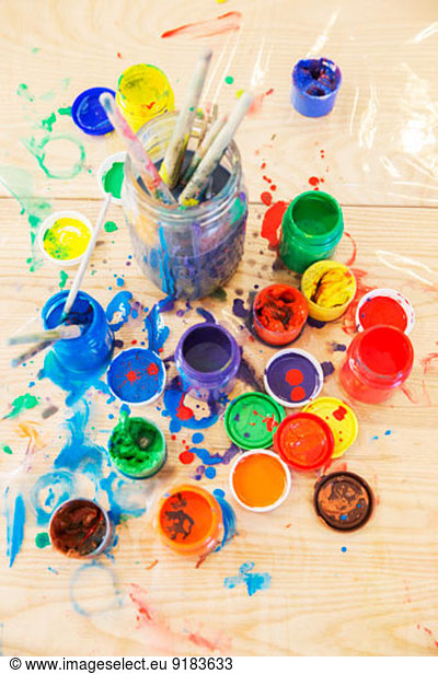 Jars of paint and paintbrushes on wooden table