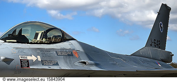 Jet fighter aircraft canopy and tail section against blue sky
