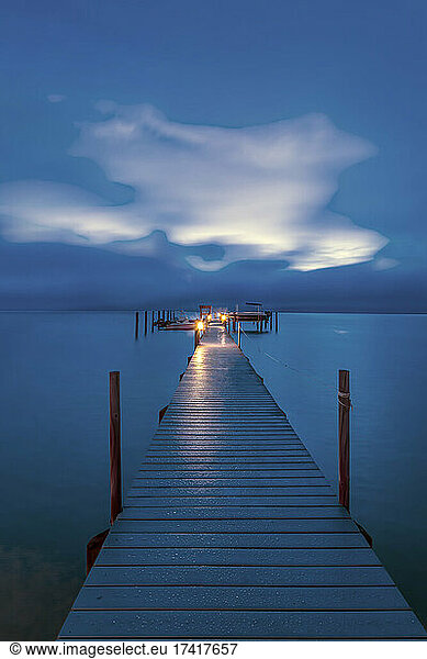 Jetty dock onto ocean at dawn with dramatic sky above.