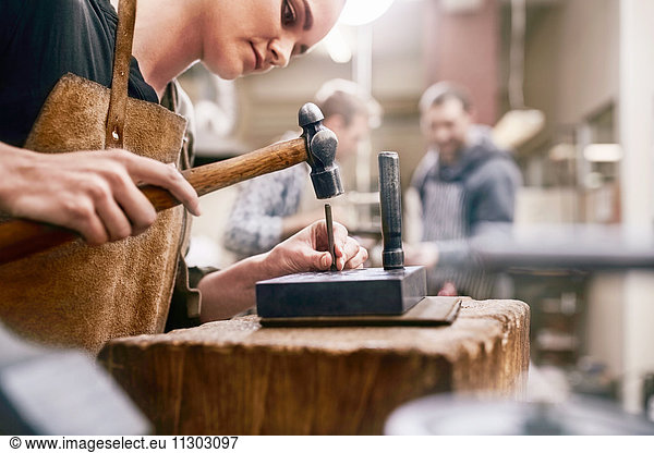 Jeweler using hammer in workshop