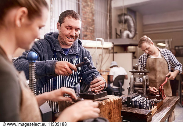 Jewelers using equipment in workshop