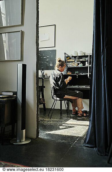 Jeweller sitting on chair working in workshop