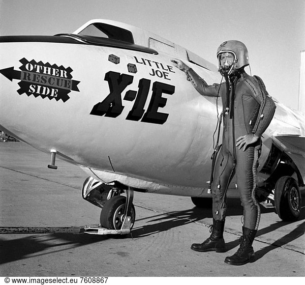 Joe Walker in a pressure suit beside the X_1E at the NASA High_Speed Flight Station  Edwards California. The dice and Little Joe are prominently displayed under the cockpit area. Little Joe is a dice players slang term for two deuces. Walker is shown in the photo wearing an early Air Force partial pressure suit. This protected the pilot if cockpit pressure was lost above 50 000 feet. Similar suits were used in such aircraft as B_47s  B_52s  F_104s  U_2s  and the X_2 and D_558_II research aircraft. Five years later  Walker reached 354 200 feet in the X_15. Similar artwork _ reading Little Joe the II _ was applied for the record flight. These cases are two of the few times that research aircraft carried such nose art.