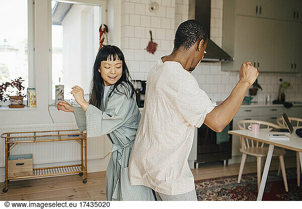 Joyful female and male friend dancing at home