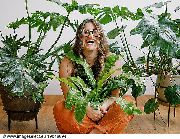 Joyful millennial woman embracing green houseplants