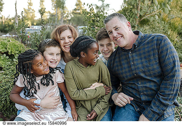 Joyful multiracial family laughing and hugging outdoors