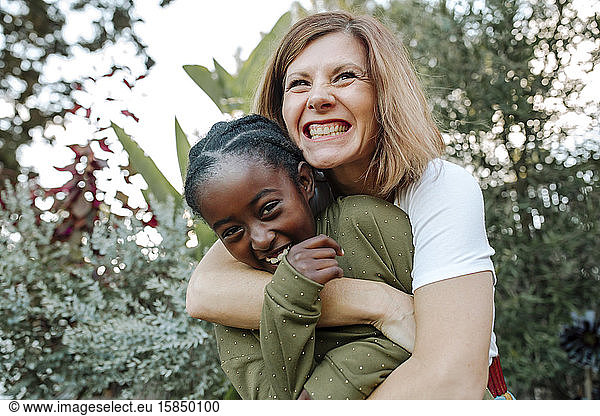 Joyful white mom hugs laughing black daughter