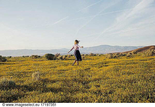 Joyful young female dancing in the desert flower field