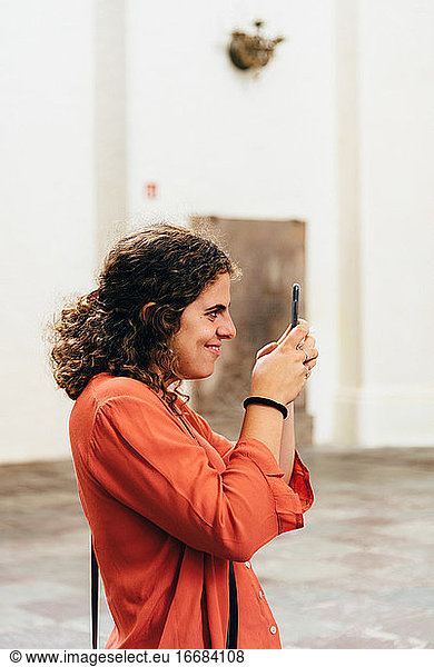Joyful young woman taking pictures with her smartphone