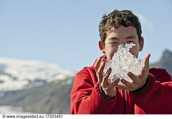 Jugendlicher hält Eis von einer Gletscherlagune in Island hoch