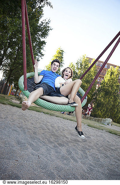 Jugendliches Paar schaukelt auf dem Spielplatz