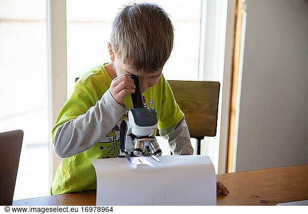 Junge arbeitet an einem wissenschaftlichen Experiment mit Mikroskop