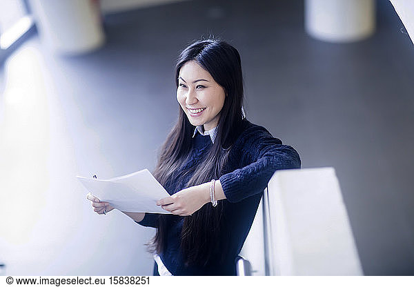 junge asiatische frau mit papier in einem büro stehend mit papier