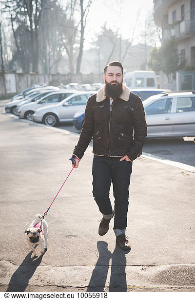 Junge bärtige Mann zu Fuß Hund auf der Straße