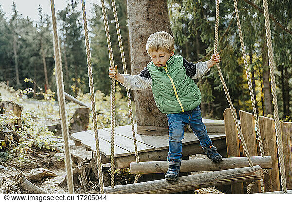 Junge beim Balancieren im Hochseilgarten im Wald im Salzburger Land  Österreich