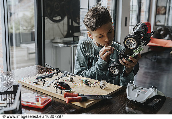 Junge beim Zusammenbau eines ferngesteuerten Spielzeugautos mit Schraubenzieher