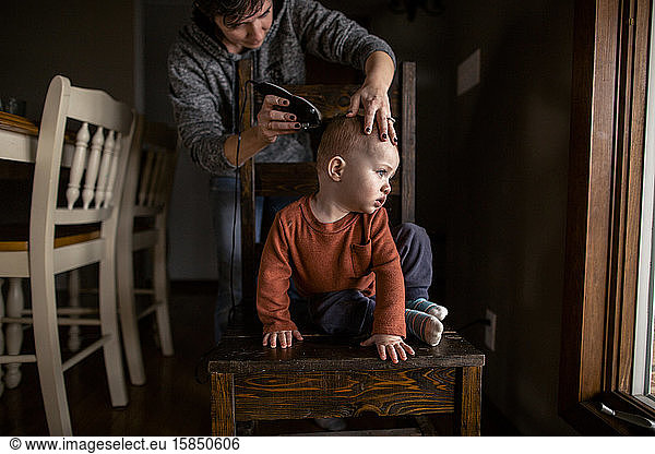 Junge bekommt zu Hause einen Haarschnitt von der Mutter  die drinnen wegschaut