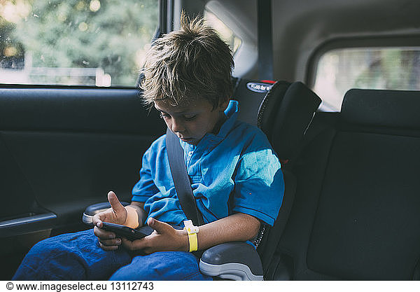 Junge benutzt Smartphone  während er im Auto sitzt
