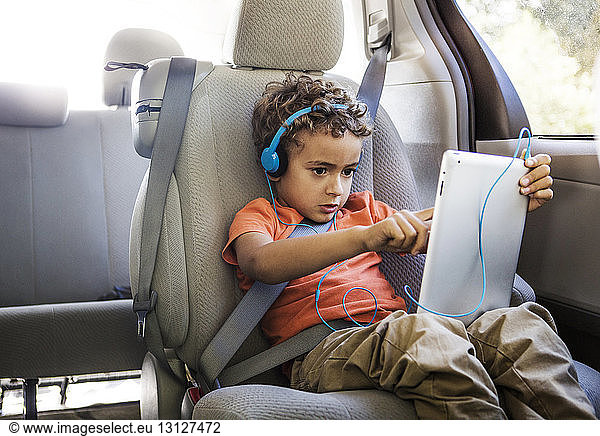 Junge benutzt Tablet-Computer  während er im Auto sitzt