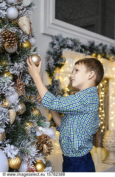 Junge beobachtet Weihnachtskugel am Baum