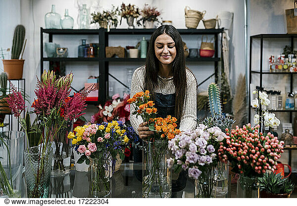 Junge Blumenhändlerin arrangiert Blumen im Geschäft