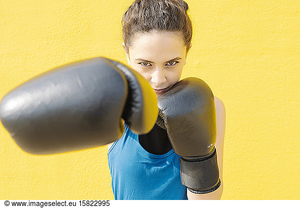 Junge Boxerin kämpft vor einer gelben Mauer