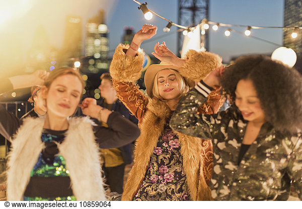 Junge erwachsene Frauen tanzen auf der nächtlichen Dachparty