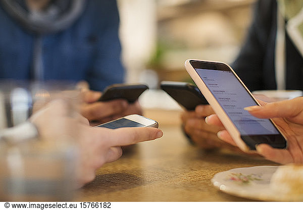 Junge Erwachsene nutzen Smartphones am Tisch