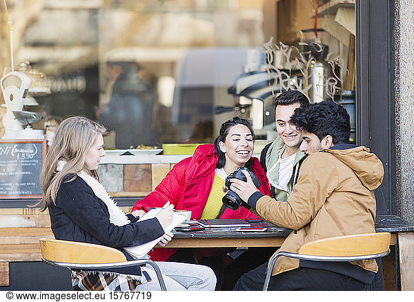 Junge erwachsene Studenten mit Digitalkamera in einem Straßencafé