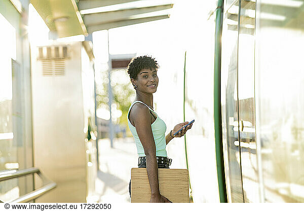 Junge Frau am Straßenbahneingang mit drahtlosen Technologien
