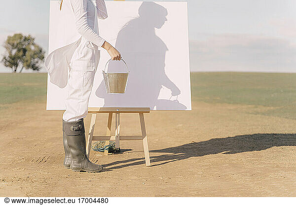 Junge Frau auf trockenem Feld  beginnt auf weißer Leinwand zu malen