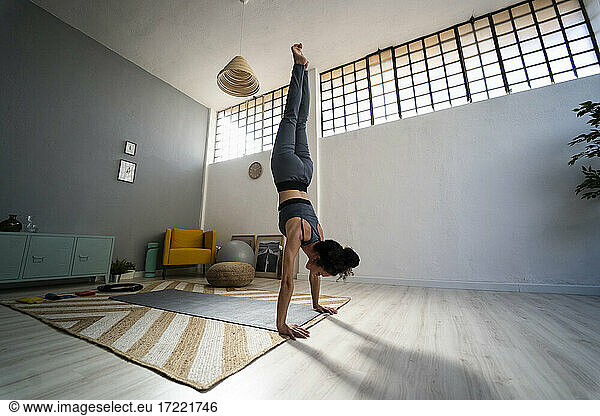 Junge Frau balanciert auf Händen im Wohnzimmer