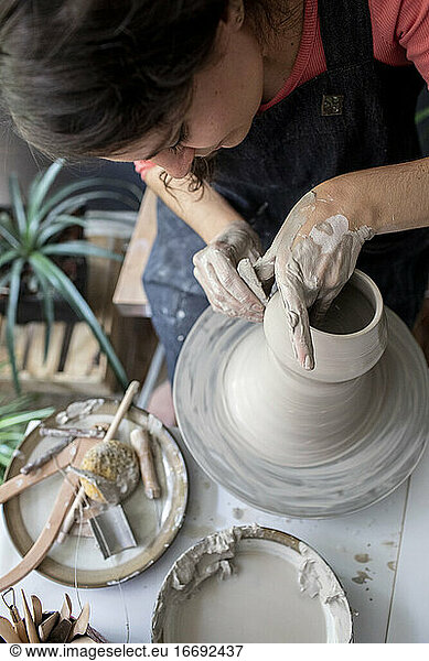 Junge Frau bearbeitet Ton in einem Keramikstudio von oben