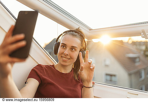 Junge Frau bei einem Videochat am Fenster im Gegenlicht