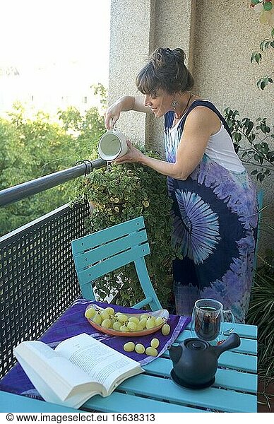 Junge Frau beim Gießen ihrer Pflanzen auf der Terrasse