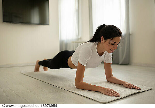 Junge Frau beim Planking auf der Matte zu Hause