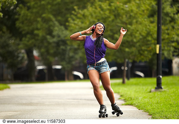 Junge Frau beim Rollschuhlaufen und Musik hören