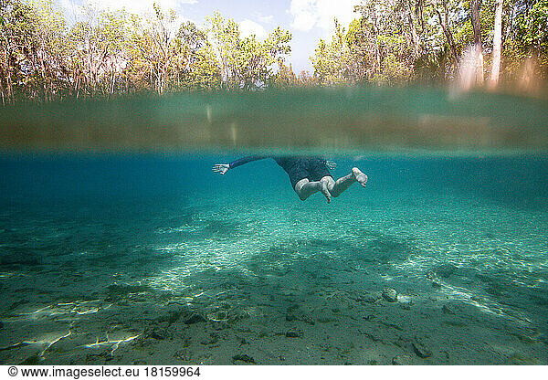 Junge Frau beim Schnorcheln unter Wasser in der Three Sisters Spring