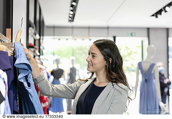 Junge Frau betrachtet ein Kleid beim Einkaufen in einer Boutique