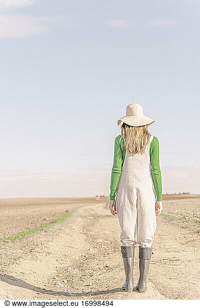 Junge Frau blickt auf trockenes Feld trockenes Feld  Rückansicht