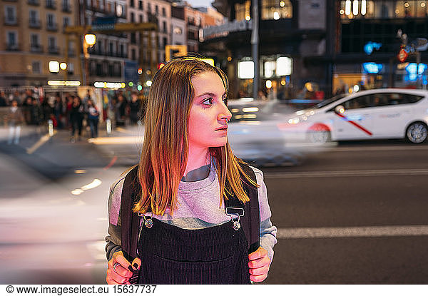 Junge Frau  die nachts in der Stadt auf der Straße steht