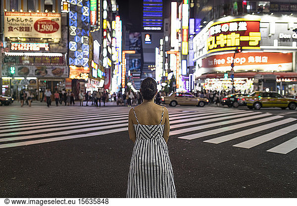 Junge Frau  die nachts nachdenkt  Menschen  die die Shinjuku-Straße überqueren  Tokio  Japan