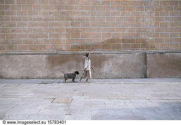 Junge Frau geht mit ihrem Hund in der Stadt spazieren